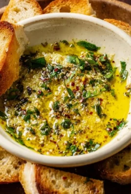 Delicious garlic olive oil dip in a small bowl with herbs and bread for dipping