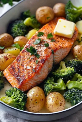 Baked salmon served with crispy potatoes and broccoli on a white plate