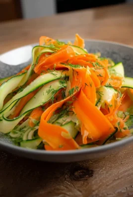 Carrot and cucumber ribbon salad garnished with fresh herbs and served in a bowl