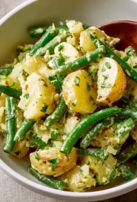 Creamy green bean potato salad with vibrant vegetables in a bowl