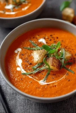 Bowl of easy creamy tomato soup garnished with fresh basil and croutons