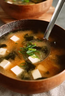 Bowl of easy gluten-free miso soup garnished with green onions and seaweed.