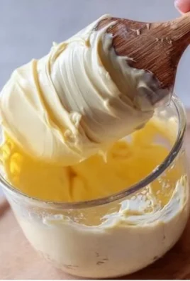 Homemade mayonnaise preparation in a bowl with ingredients.