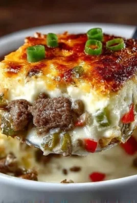 Low Carb Philly Cheesesteak Casserole topped with melted cheese and peppers
