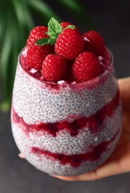 A bowl of raspberry chia pudding topped with fresh raspberries and mint leaves.