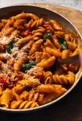 Delicious roasted red pepper pasta topped with herbs and cheese.