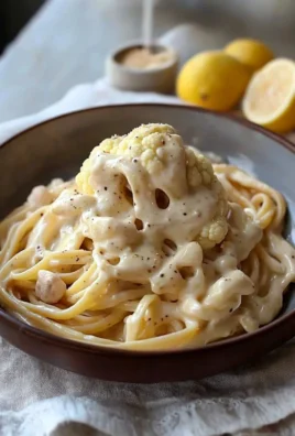 Creamy Cauliflower Alfredo sauce served over pasta with fresh herbs.
