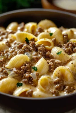 Creamy beef and shells dish served in a bowl with fresh herbs