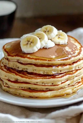 Fluffy banana pancakes topped with syrup and fresh bananas