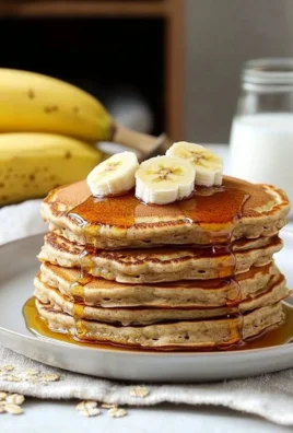Healthy banana oatmeal pancakes stacked on a plate with fresh banana slices