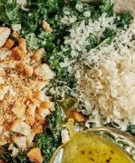 A vibrant Lemon Parm Kale Salad topped with fresh lemon and Parmesan cheese.