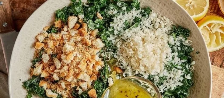 A vibrant Lemon Parm Kale Salad topped with fresh lemon and Parmesan cheese.