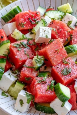 Refreshing watermelon cucumber feta salad in a bowl with mint leaves.