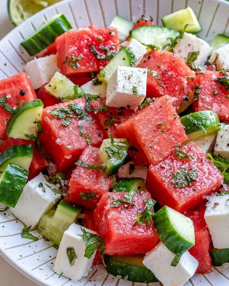 Refreshing watermelon cucumber feta salad in a bowl with mint leaves.