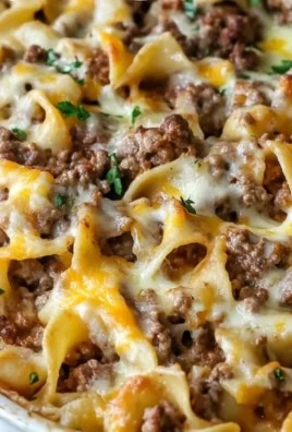 Sour cream beef noodle casserole served in a baking dish with melted cheese on top