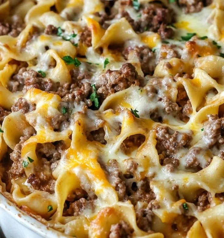 Sour cream beef noodle casserole served in a baking dish with melted cheese on top