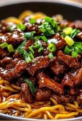 Plate of sticky beef noodles garnished with herbs and sauce.